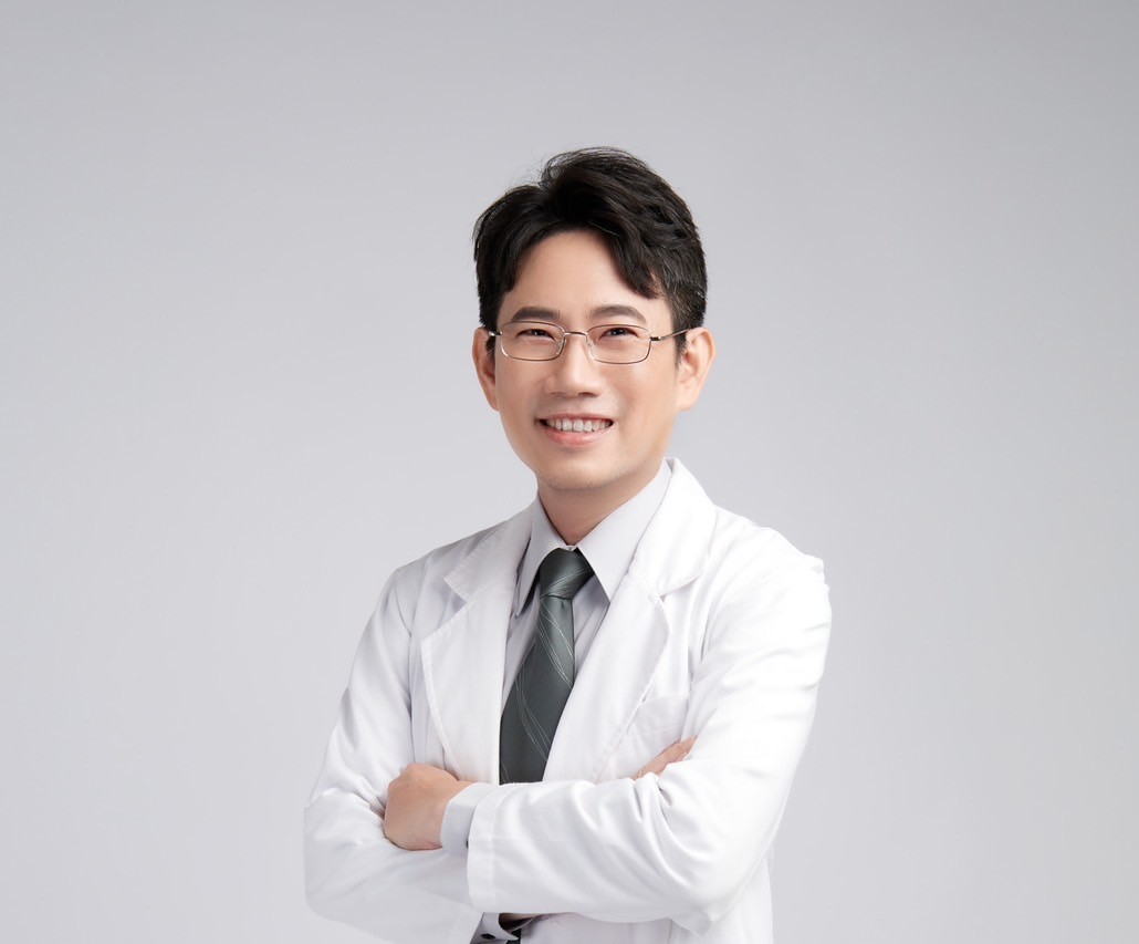 一位戴眼鏡、穿白袍打領帶的男士雙手交叉微笑的半身照